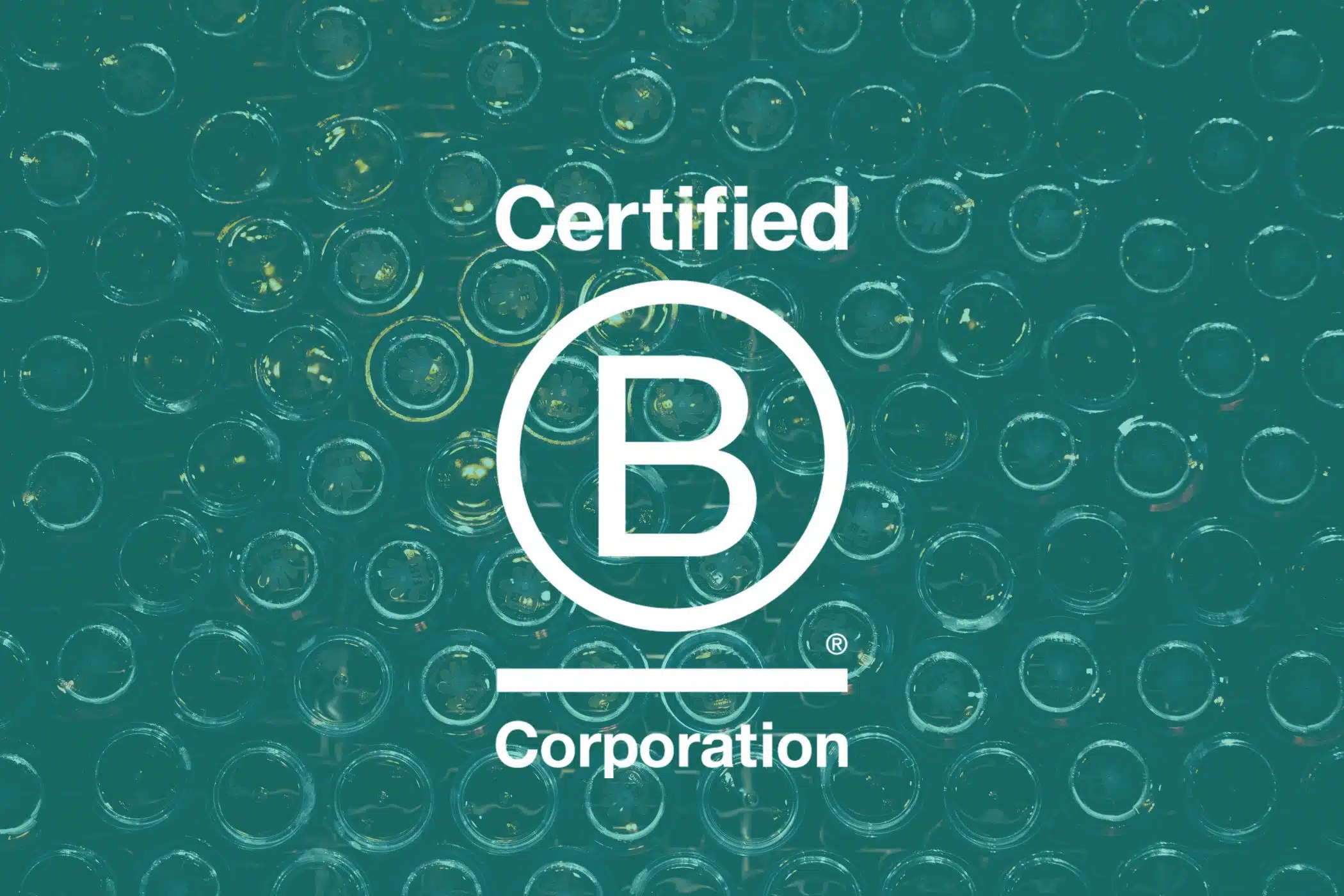 Certified B Corporation logo over a background of stacked glass bottles.